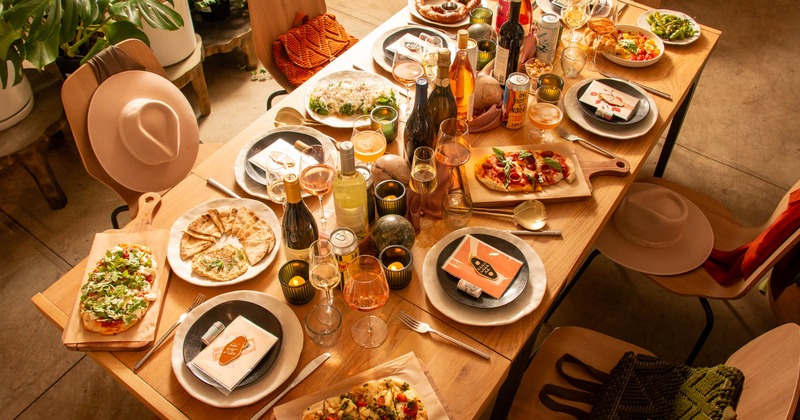 A rustic wooden table is laden with various dishes, drinks, and candles