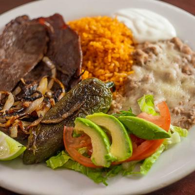 Grilled steak, with salad, rice, and refried beans.