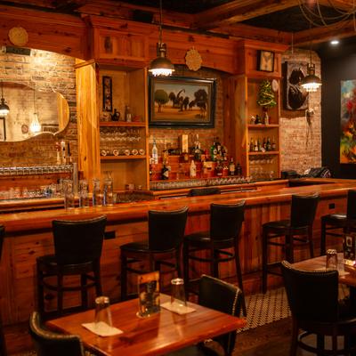 Bar area, bar, chairs, drink rack behind.