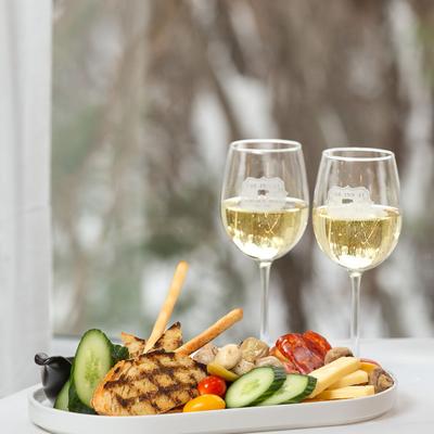 Grilled chicken platter with vegetables and two glasses of white wine.