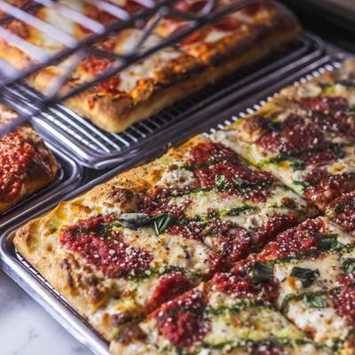 Sicilian style pizza with cheese, tomato, and basil.