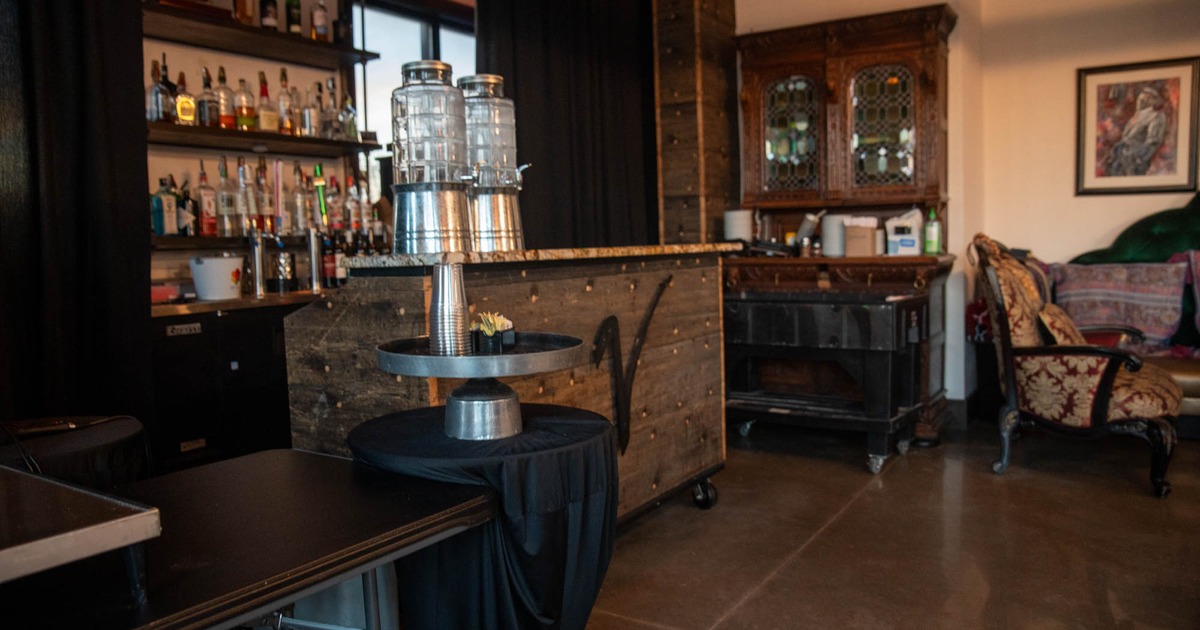 Bar with a cabinet, shelves of liquor, and beverage dispensers on a counter