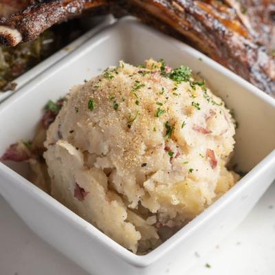 Garlic mashed potatoes in a square white bowl.