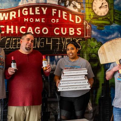 Owner and staff, a group portrait shot in front of a mural wall.