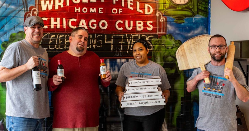Owner and staff members posing in front of a mural wall