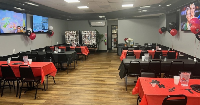 A banquet hall featuring red and black tablecloths on tables, and decorative balloons