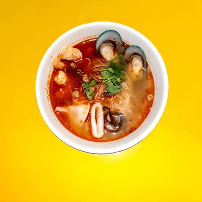 Bowl of seafood noodle soup topped with fresh herbs.