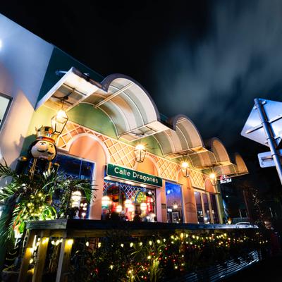 Iluminated facade of restaurant at night with Calle Dragones sign inside Front.