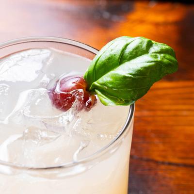 Passport cocktail garnished with a mint leaf and a grape.