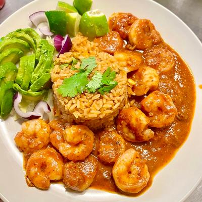 Shrimp in a spicy sauce, served with rice and avocado slices.