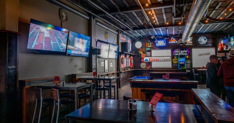 Tables with bar stools and TV screens on the wall