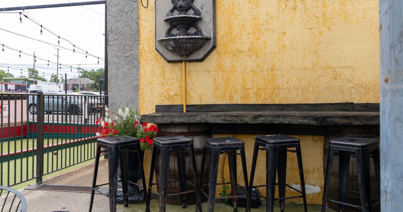 Exterior, wall table and bar stools in the outdoor seating area  by the Bocce courts at Coco's Italian Market