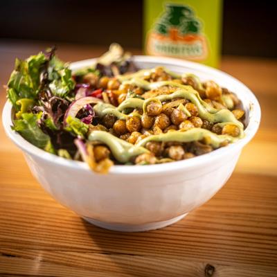 Chickpea bowl featuring roasted chickpeas, a salad and a green sauce drizzle.