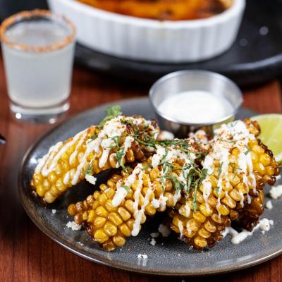 Mexican street corn topped with crema, served with dip.