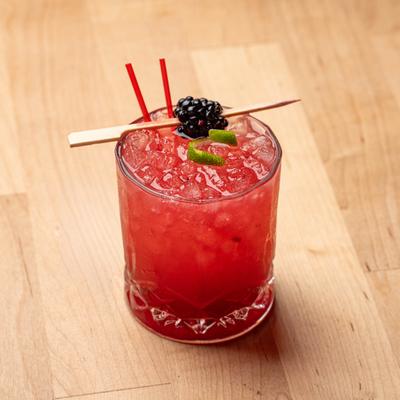 Blackberry Mule served in a rocks glass, garnished with a blackberry and a lime peel.