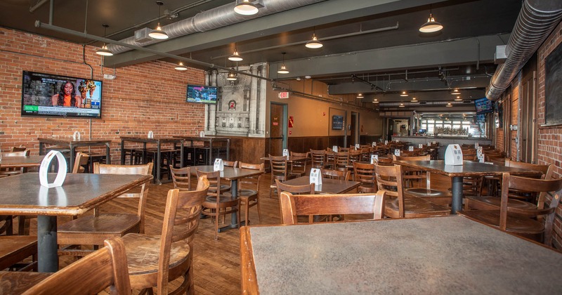Interior, tables and chairs in seating area with tv on the wall