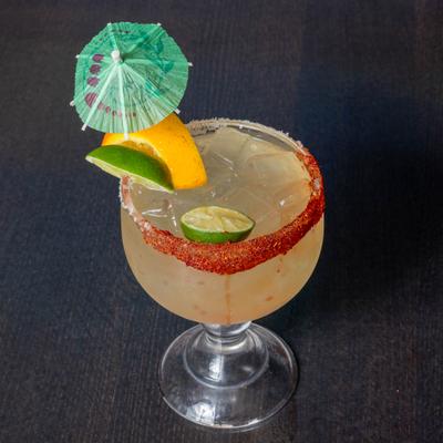 Classic Margarita in a glass with chili rim, citrus garnishes and an umbrella.
