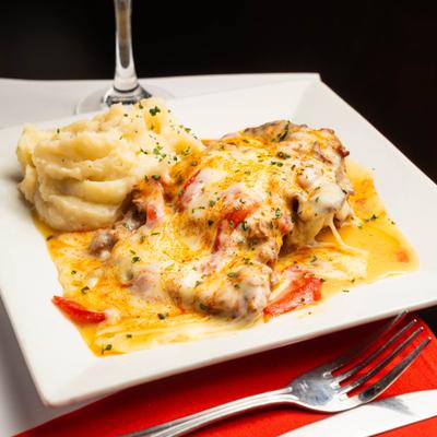 Cheesy baked dish with mashed potatoes on a white plate