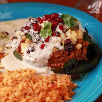 Stuffed poblano topped with nogada sauce, served with sour cream, rice, and beans