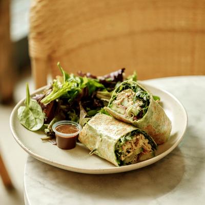 Cut wrap served with mixed greens on a round plate.