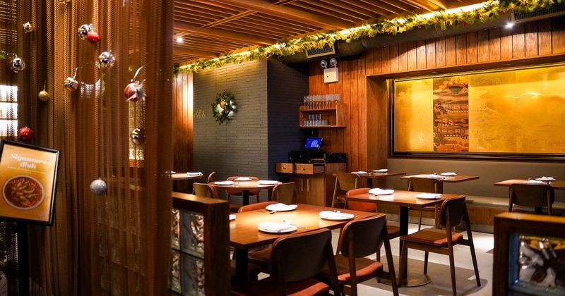 A warmly lit interior with wooden furniture, festive decorations and elegant artwork.