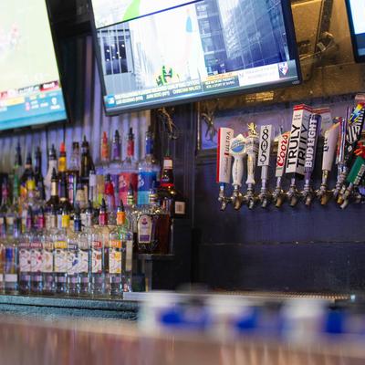 The bar area with beer taps, liquor bottles on the shelves, and TVs.