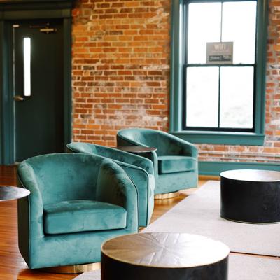 Modern lounge with teal velvet chairs and round tables.