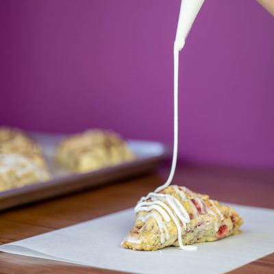 Lemon rosemary scone being drizzled with white icing.