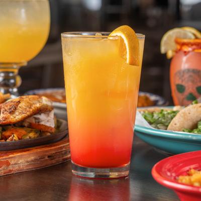 Tequilla Sunrrise cocktail served with food on a table.