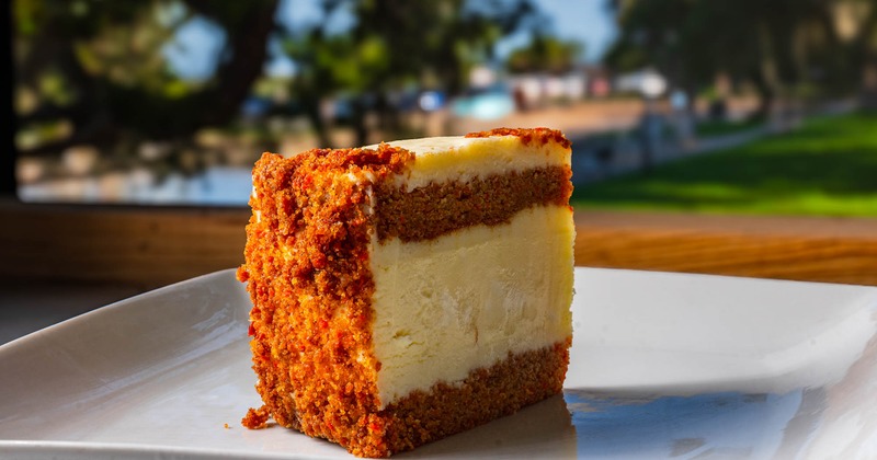 Carrot Cake Cheesecake slice on a table in an outdoor setting, close up