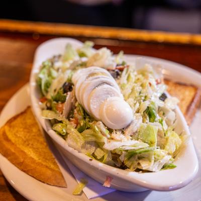 Porch House Salad in a oval dish, topped with boiled egg and served with toast.