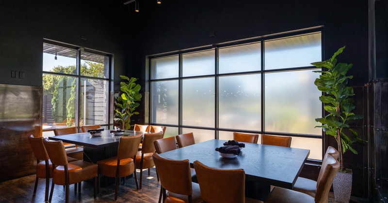 Dining area with leather chairs, dark wooden tables, and large frosted window