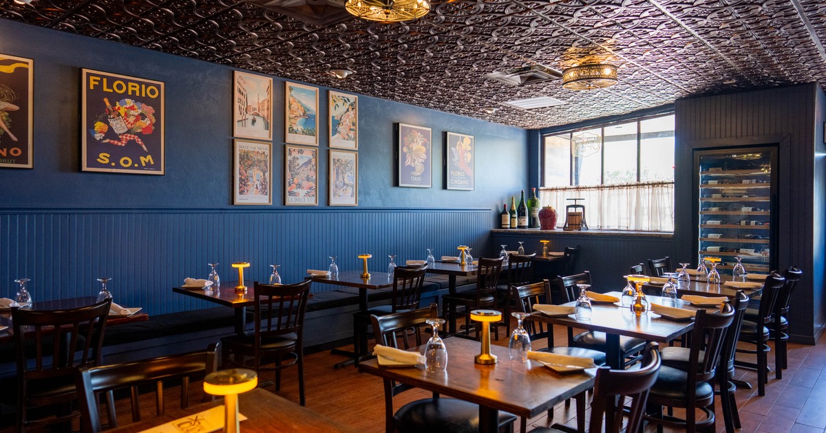 A stylish interior - blue walls, vintage posters, dark wood furniture and glowing table lamps