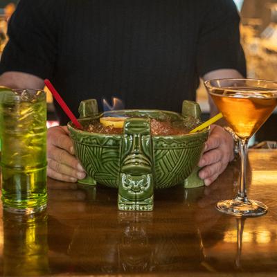 Large tiki cocktail bowl with drinks on a wooden table.