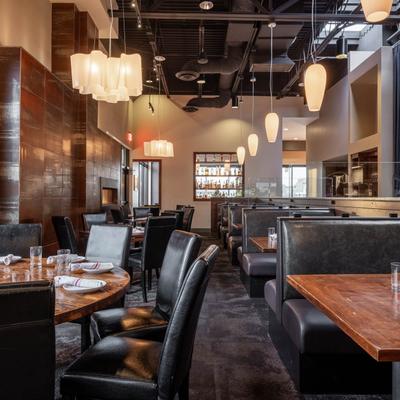 Elegant interior with booth and standard seating, wooden tables, and pendant lights.