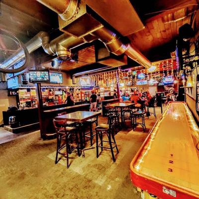 Interior with tables, chairs, TVs, and a shuffleboard table.