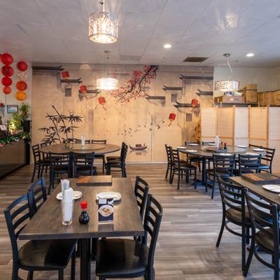 Chinese restaurant interior with tables, red lanterns, and a wall mura.