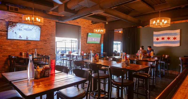 Interior with exposed brick walls, wooden tables, TV screens and high-top seating