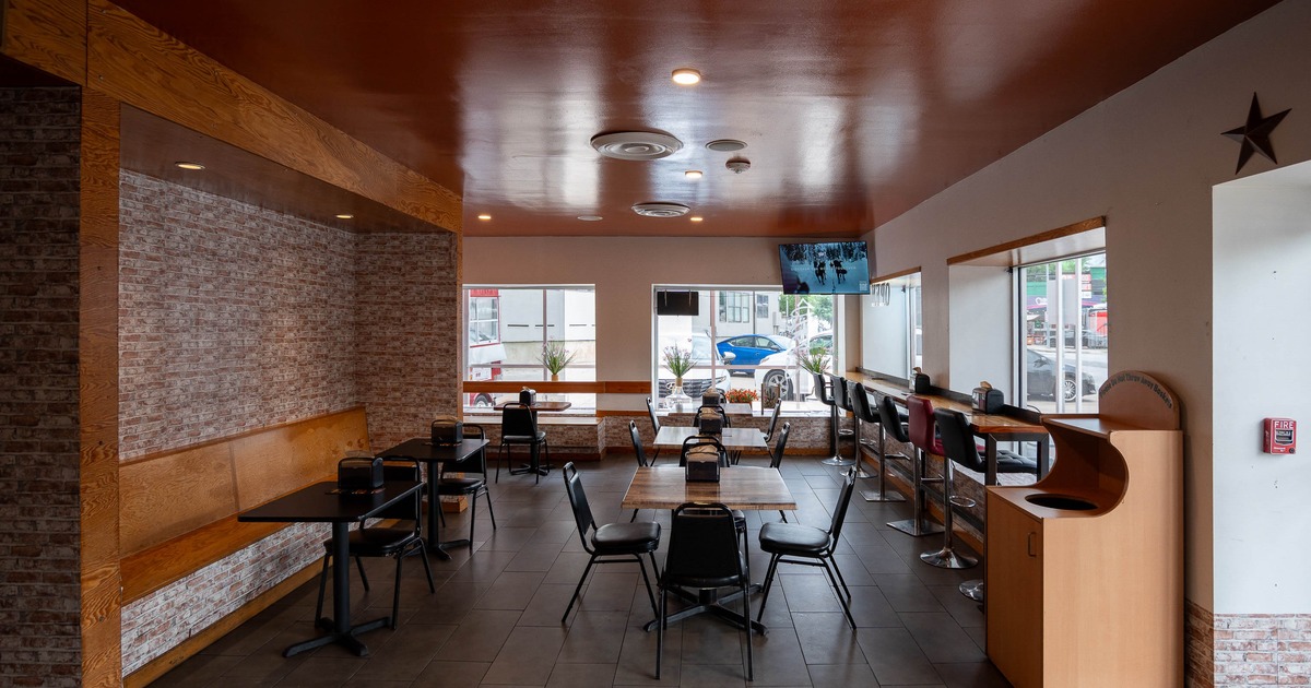 Cozy restaurant interior with brown ceiling and brick walls, tables and chairs are arranged neatly