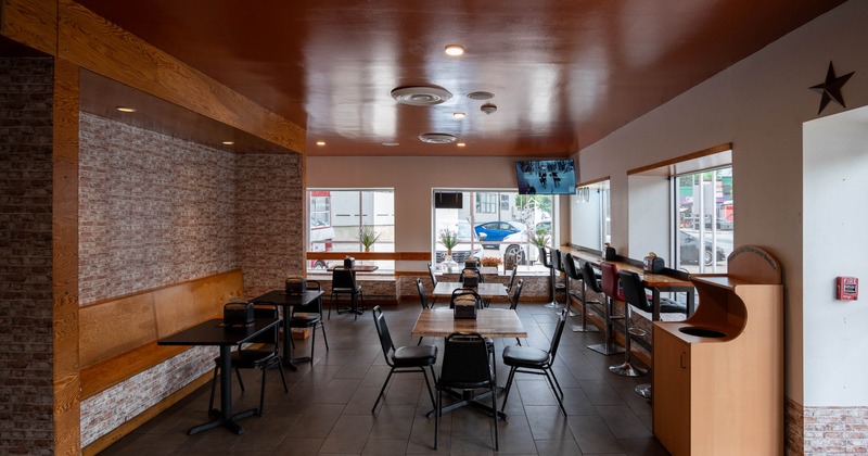 Cozy restaurant interior with brown ceiling and brick walls, tables and chairs are arranged neatly