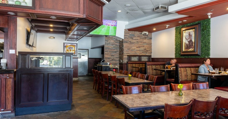 Interior of a restaurant featuring dark wooden tables, chairs, and a stone wall