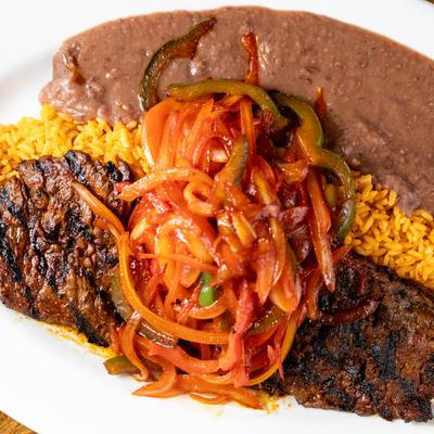 Grilled skirt steak, with onions, peppers, yellow rice, and refried beans.