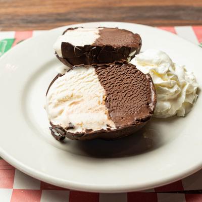 Tartufo dessert served on a white plate, garnished with whipped cream.