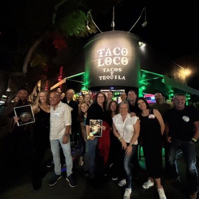Group of smiling people standing in front of a sign 