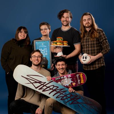 People posing for a photo holding various stuff.