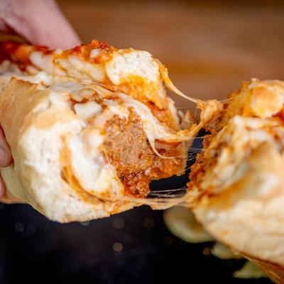 Hands holding a meatball sandwich.