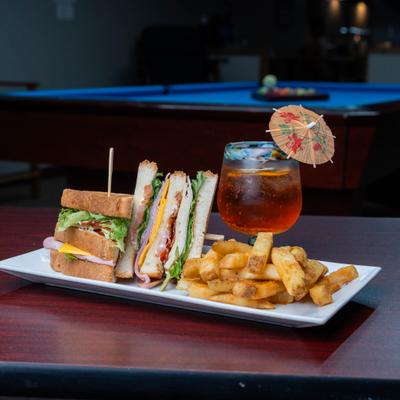 Club sandwich served with fries and a tropical cocktail.