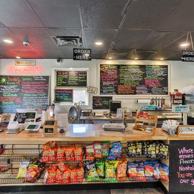 Counter area with multiple chalkboard menus and display rack with snacks.