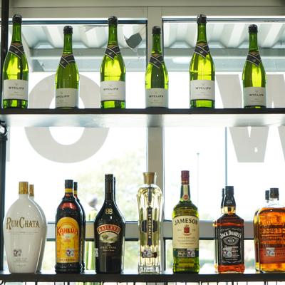 Champagne bottles and various liquor bottles displayed on two shelves.
