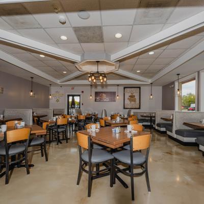 Restaurant dining room with wooden tables, overhead lights and art on the walls.